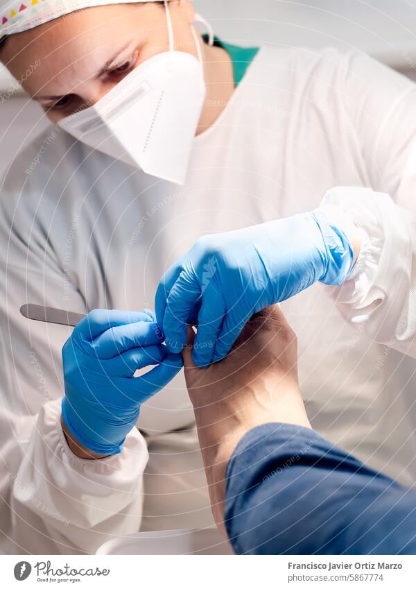 Female podiatrist doing chiropody in her podiatry clinic. Selective focus woman nail callus foot patient pedicure medicine bunion chiropodist health doctor care