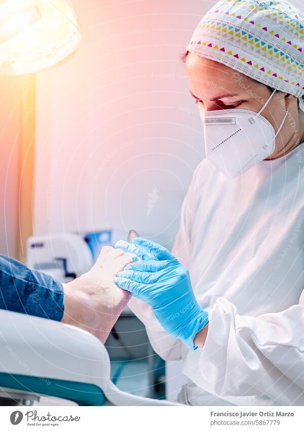 Female podiatrist doing chiropody in her podiatry clinic. Selective focus woman nail callus foot patient pedicure medicine bunion chiropodist health doctor care