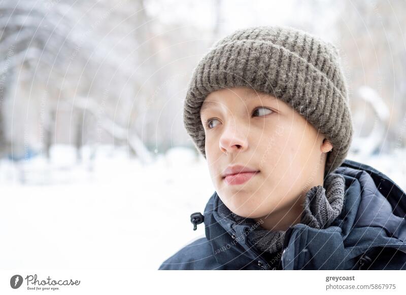Young boy in winter clothing child hat jacket outdoor snow landscape Caucasian young looking side portrait cold knit season weather white background