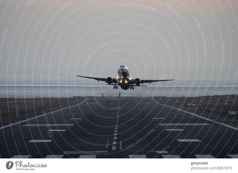 Airplane taking off from runway at dusk airplane takeoff aircraft ocean lights sky travel transportation flight aviation airport evening ascent jet departure