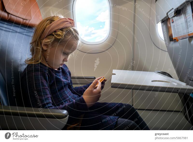 Caucasian girl sitting in airplane seat window toy caucasian young child interior aircraft travel flight passenger playing airliner journey transportation cabin
