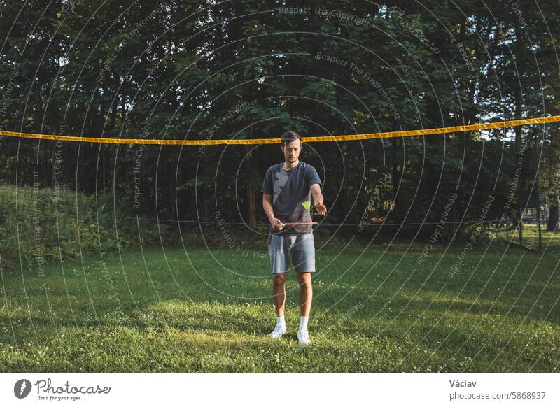 Black-haired badminton player practices his strokes on the grass court. Individual technique training. Amateur concept of the sport. The joy of the game athlete