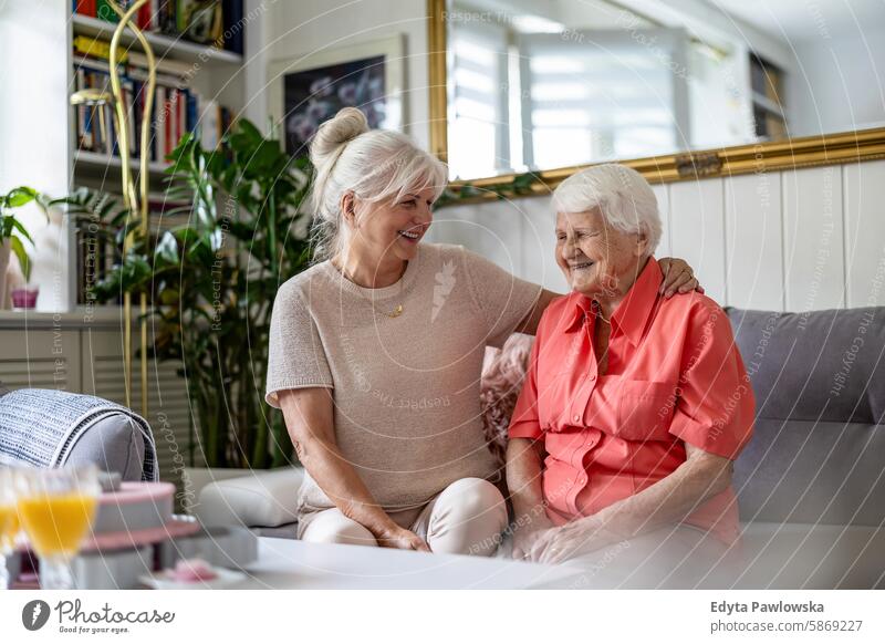 Happy senior woman with her adult daughter at home smiling happy enjoying positive contented people mature female elderly house old aging domestic life