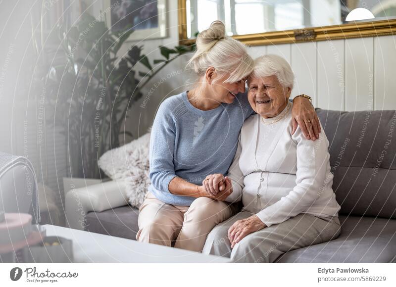 Happy senior woman with her adult daughter at home smiling happy enjoying positive contented people mature female elderly house old aging domestic life