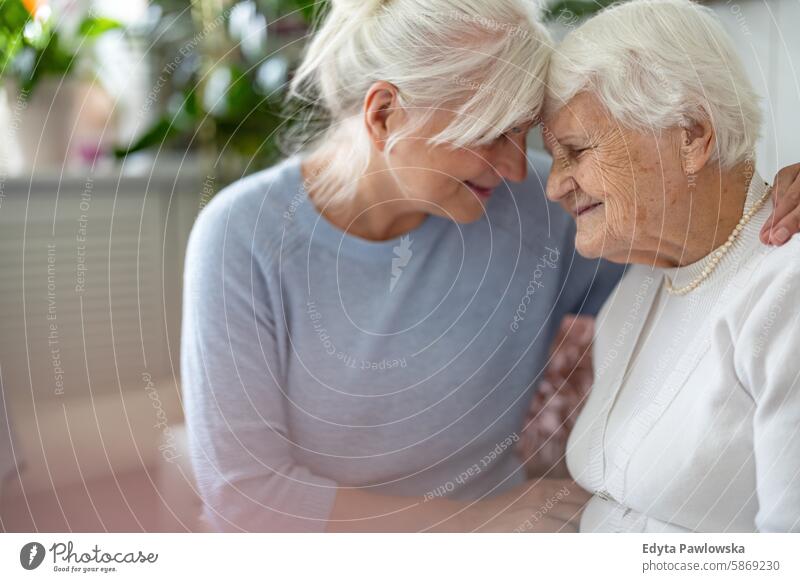 Happy senior woman with her adult daughter at home smiling happy enjoying positive contented people mature female elderly house old aging domestic life