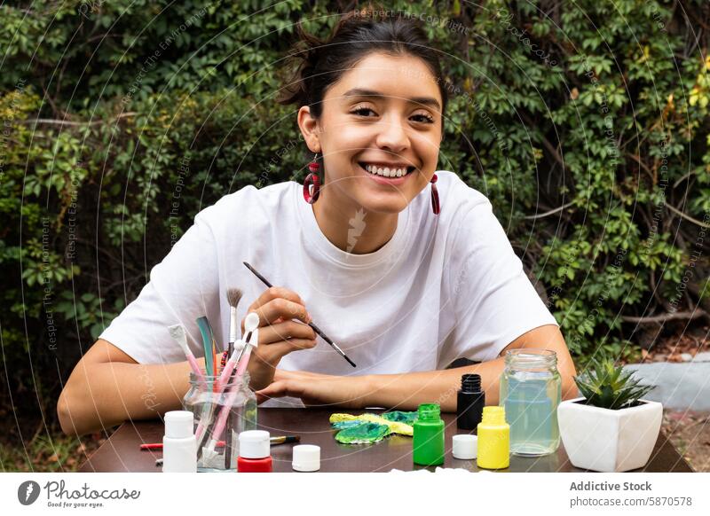 Young woman painting clay crafts outdoors with a smile brush nature colorful art creative hobby cheerful young activity crafting artistic leisure enjoyment