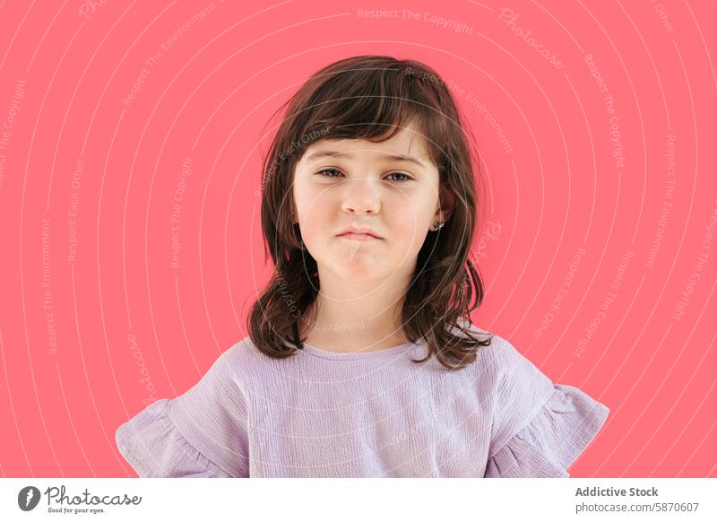 Portrait of a young girl with a neutral expression on red portrait child studio red background kids lavender shirt calm fashion serious direct gaze