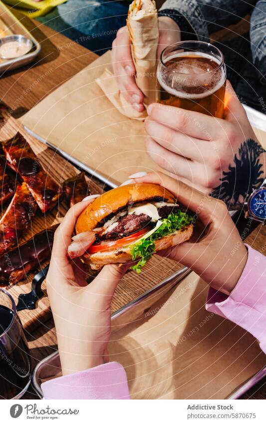 Close-up of friends enjoying a variety of barbecue foods burger rib wrap drink gathering casual sharing meal cold vibrant scene eating holding enjoyment