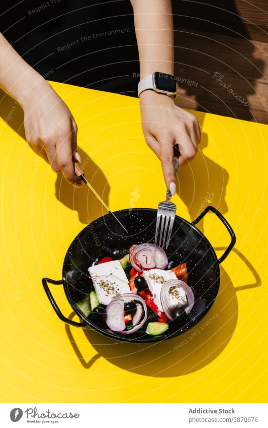 Hands preparing a fresh Greek salad in a skillet outdoors greek healthy eating meal preparation diet nutrition hands arranging vibrant contrast yellow tomato