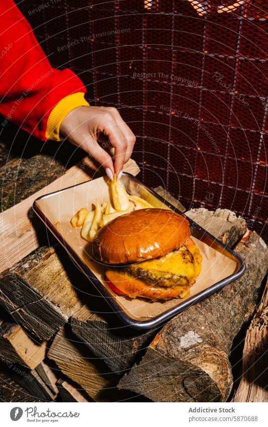 Burger and fries on rustic wooden setting at a barbecue burger fry cheese slab meal cozy person hand grabbing dinner lunch eat food dish tray fresh topping