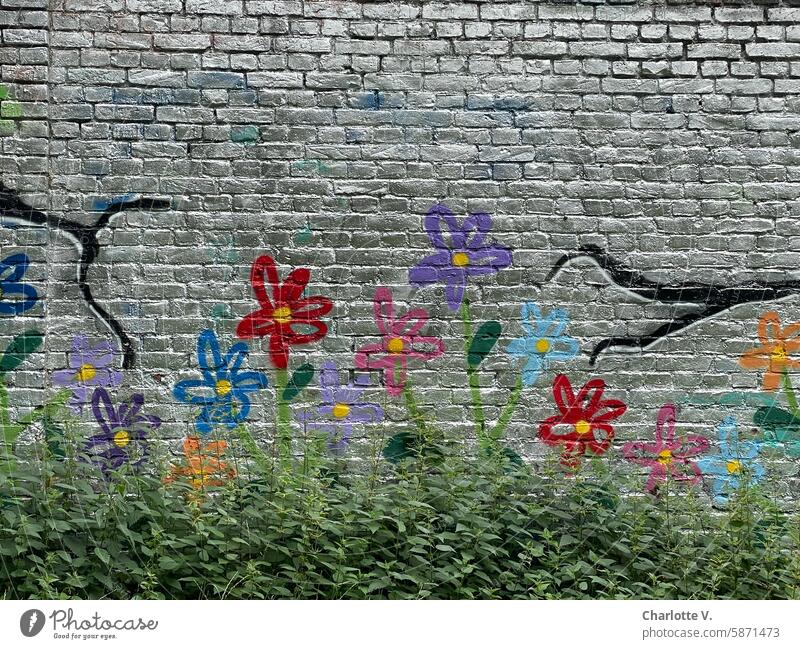 Flower meadow I Painted flowers on a silver sprayed brick wall with weeds in front of it Wall (building) painted flowers Graffiti Weed beautification decoration