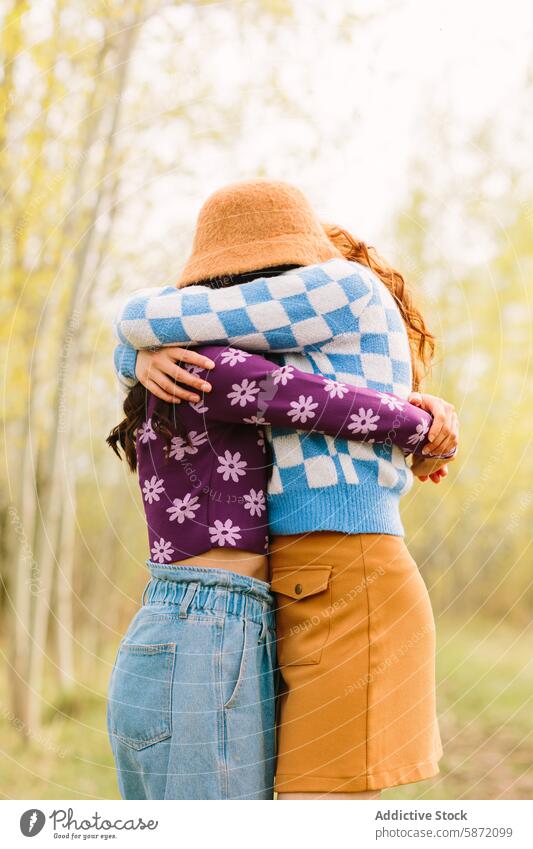 Intimate embrace of two anonymous friends in a forest setting friendship affection closeness colorful outerwear style vibrant warmth hug nature outdoors trees