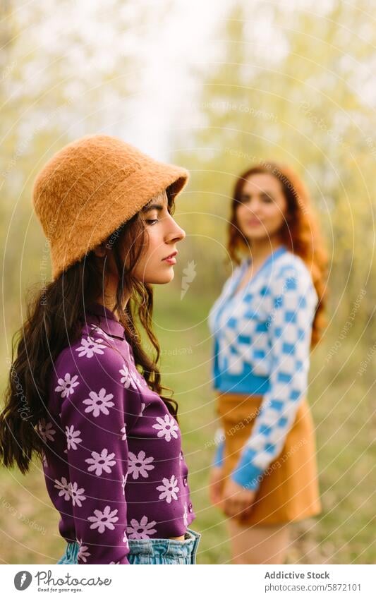 Two women enjoying a leisurely day in the woods woman friend nature trees blooming serenity thought beret sweater floral style fashionable tan background blue