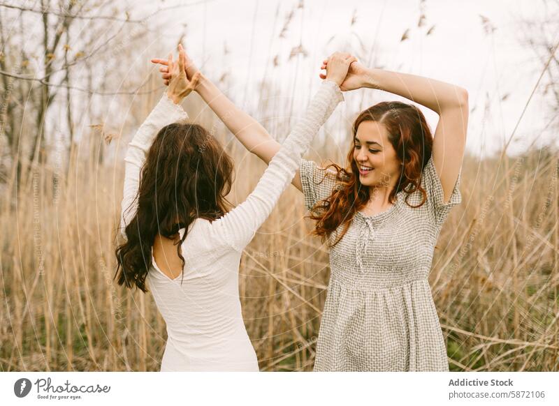 Two young women enjoying a playful moment in the woods woman friend dance happiness freedom nature expression outdoor hand hold celebrate unrecognizable smile