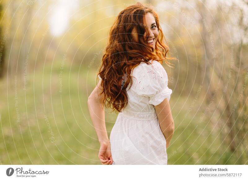 Young woman with red hair enjoying nature in the woods curly forest spring smile walk freedom happiness dress white sunlit outdoors happy daytime leisure