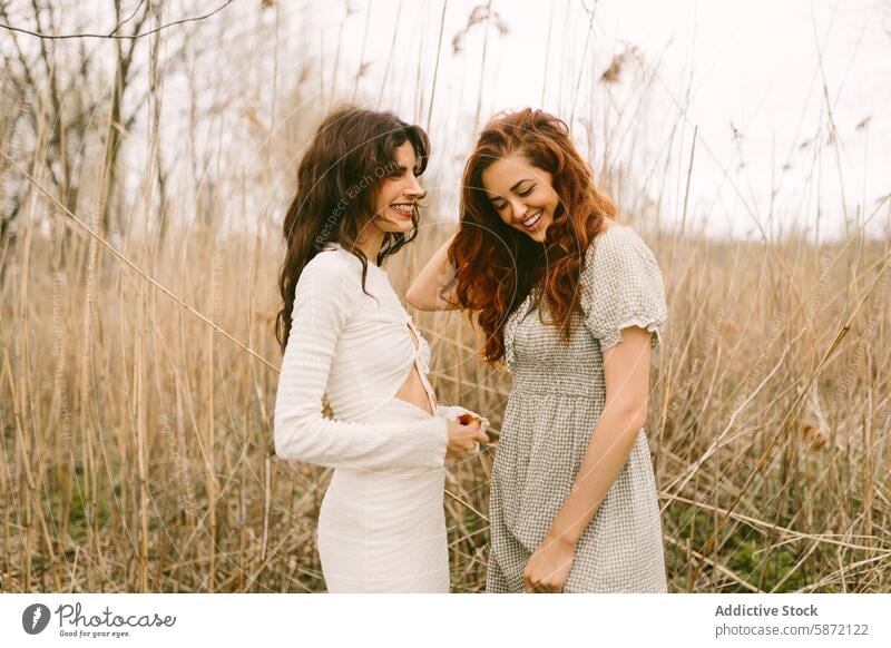 Two women laughing together in a natural woodland setting woman friend nature casual dress joy happiness outdoor reed serene day young smile moment sharing