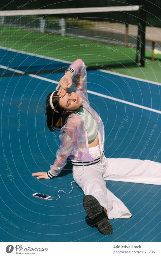 Young woman enjoying music at a sunny tennis court young leisure headphones smartphone relaxation lifestyle vibrant enjoyment sunny day sportswear outdoor