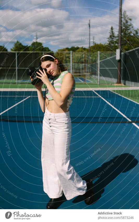 Fashionable Woman Posing with Vintage Camera on Tennis Court woman tennis court style sunny casual young stylish activity relaxation summer sport recreational