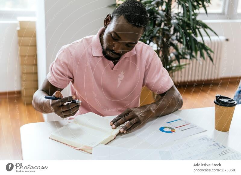 African American man working in a bright coworking space african american workspace documents charts coffee cup indoor professional entrepreneur self-employed