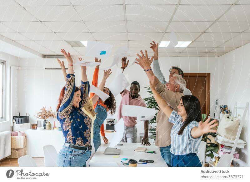 Diverse team celebrating success in a coworking space celebration professional paper office diverse multiethnic multiracial teamwork throwing air cheerful smile