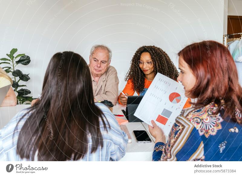 Diverse team discussing strategy at coworking space discussion collaboration professional diagram african american caucasian man female colleague technology