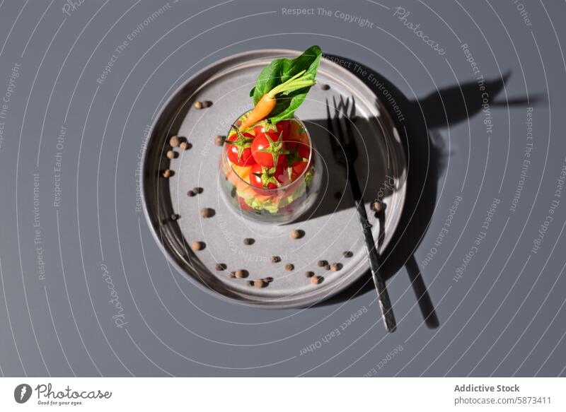 Top view of a fresh salad in a glass on a gray plate vegetable top view transparent glass gray background healthy colorful greens cherry tomato carrot textured