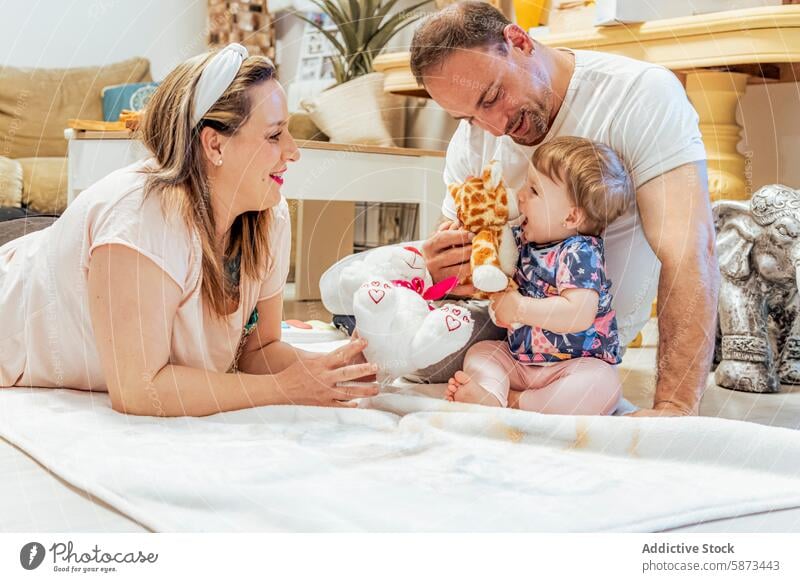 Family playing with baby on living room floor family home parent mother father toy giraffe joy curiosity delight cozy togetherness child toddler infant bonding