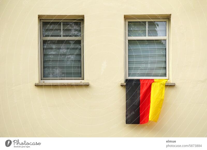 A German flag hangs from one of the two windows with the blinds closed Foot ball football fan black-red-gold EM WORLD CUP UEFA European Championship World Cup