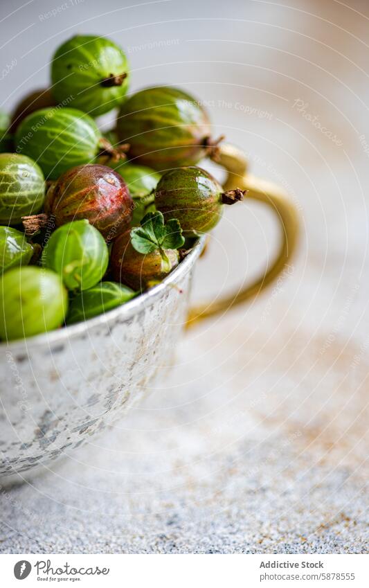 Close-up view of ripe organic gooseberries in a rustic cup gooseberry fruit fresh metal cup close-up vibrant green red natural soft-focus background food