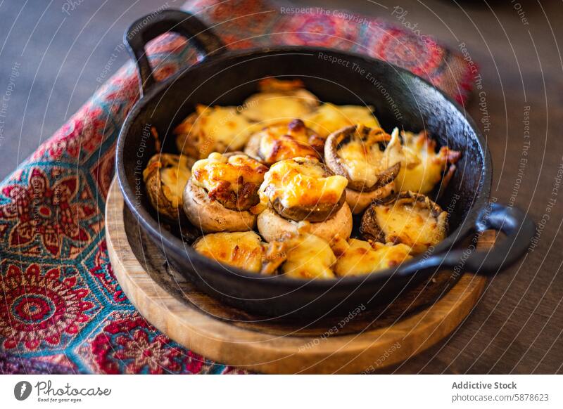 Baked mushrooms stuffed with sulguni cheese in skillet baked rustic wooden table colorful fabric background food dish appetizer meal cuisine gourmet tasty