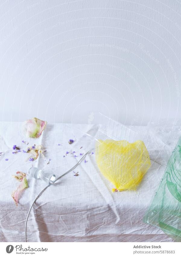 Artistic display of dried flowers and a yellow net on fabric artistic minimalist white fabric texture purple petal delicate subtle lighting arrangement vivid