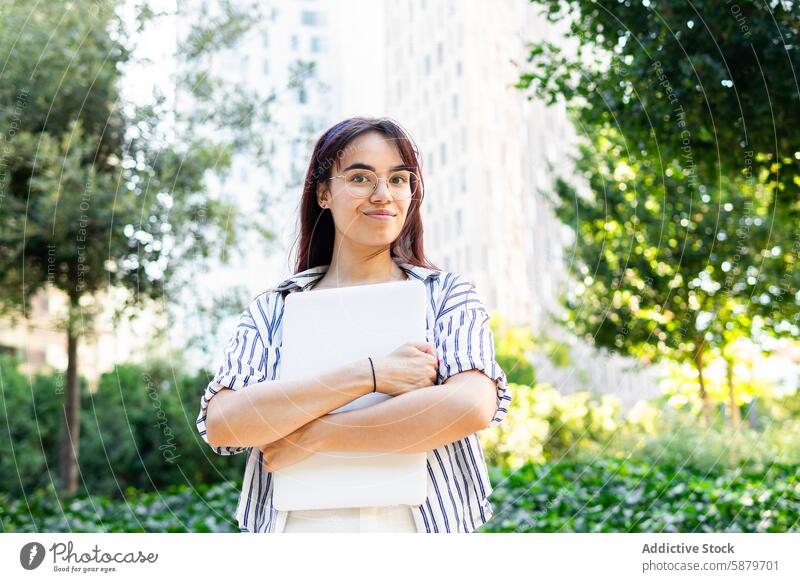 Young woman holding a laptop outdoors in spring urban park city greenery building cheerful smiling young female technology professional student education work