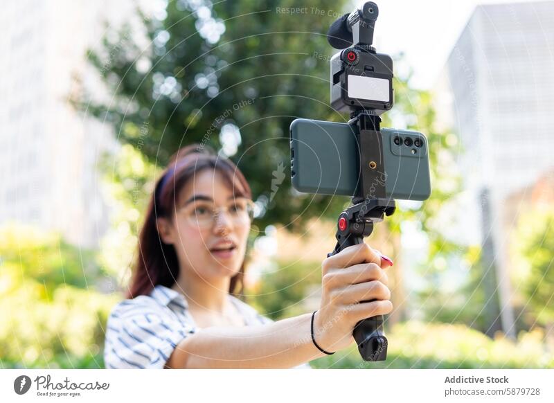 Young woman recording with smartphone stabilizer outdoors video park technology modern videography sunny young female gadget mobile digital capture media