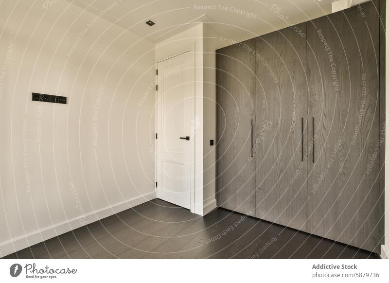 Minimalist interior design of a modern bedroom corner minimalist white door dark wood flooring textured gray closet contemporary sleek home architecture wall