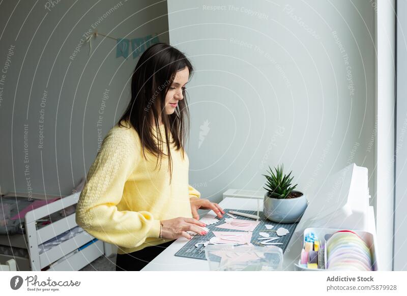 Young woman crafting with paper at a creative workspace plant supplies focus engage young organized decorate indoor hobby artistic design handmade workstation