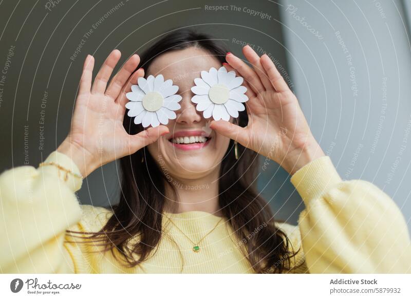 Young woman holding paper flowers over her eyes craft daisy creative handmade joy smile young female crafting art hobby leisure activity cheerful happy fun