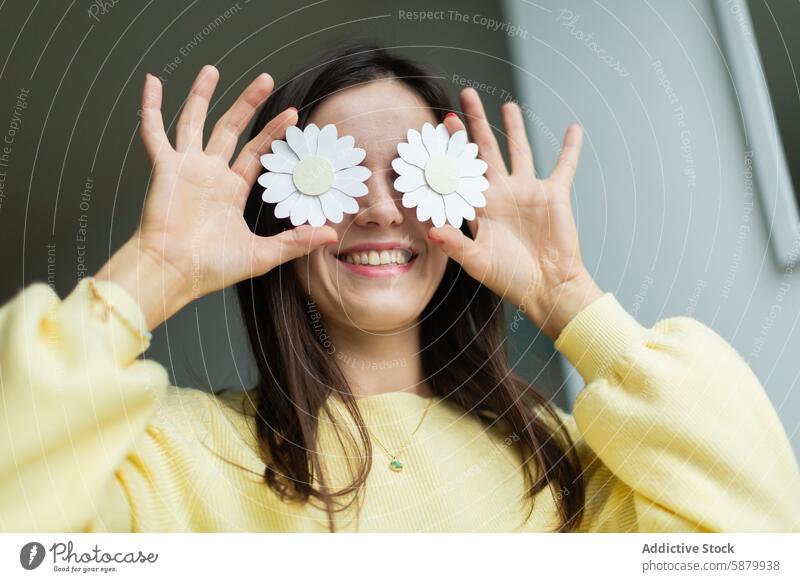 Young woman using paper flowers as playful eye covers craft creativity joy casual smiling happiness handcraft hobby art design decorative cheerful young adult