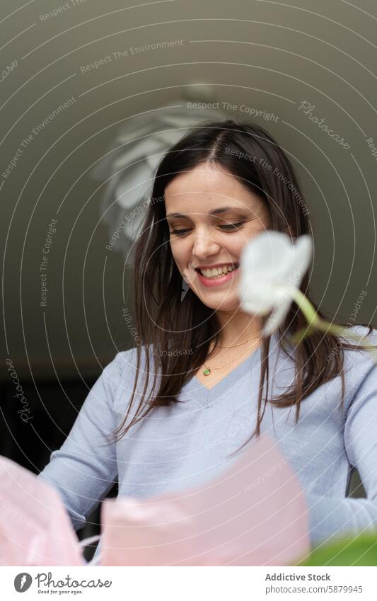 Young woman smiling as she enjoys paper crafting smile hobby handmade creativity art flower young adult female happy leisure indoor casual enjoyment workshop