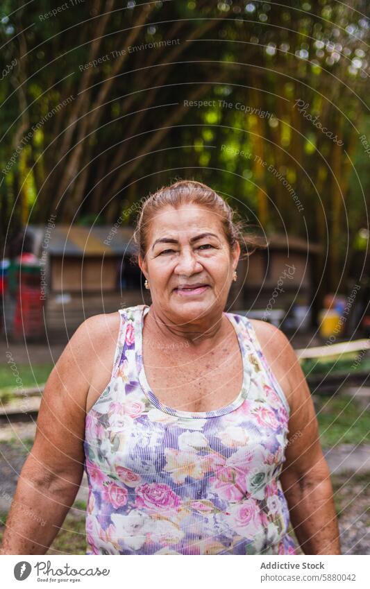 Elderly Colombian woman standing in a rural setting elderly colombian outdoor greenery tank top floral confident senior background nature landscape portrait