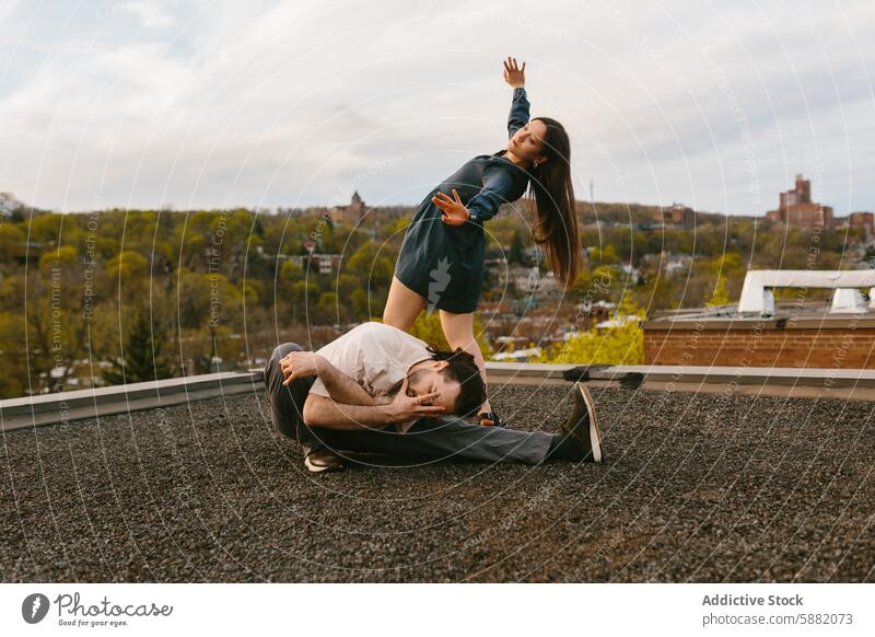 Couple performing a dance move on a city rooftop cityscape couple pose man woman twilight dynamic performance backdrop urban outdoors recreational fashion