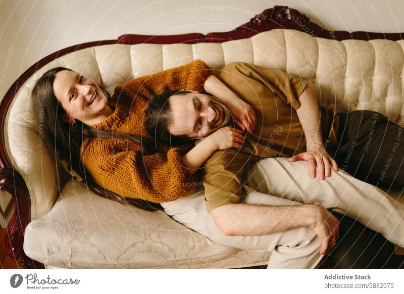 Joyful couple laughing together on a vintage sofa woman joyful happy looking at camera eyes closed looking away ornate playful expression relaxed comfort indoor