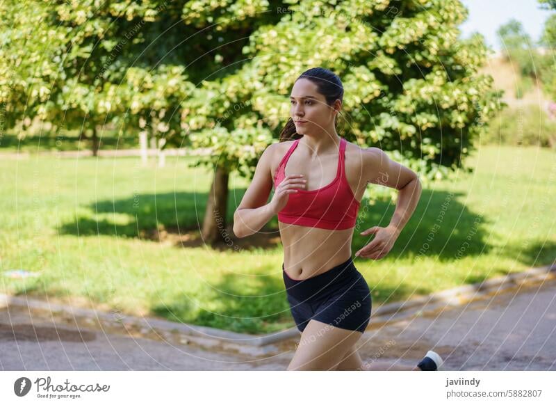 A young woman is running outdoors in a park, dedicated to fitness and maintaining a healthy lifestyle active athlete athletic cardio daytime dedication
