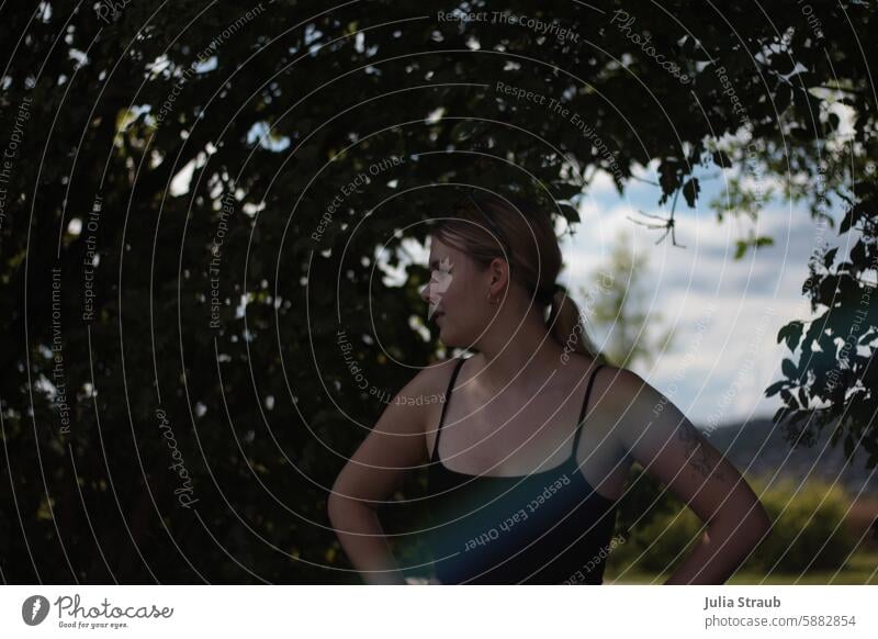 In the shade Shadow Woman Blonde Braids Rainbow tattoo Summer out plants leaves Hedge cooling warm Sunglasses