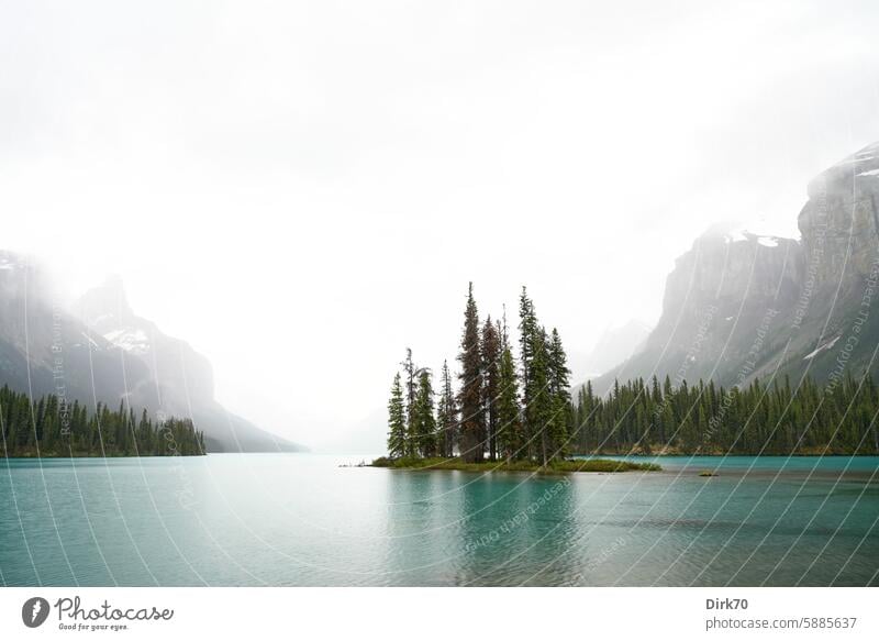 Spirit Island in Maligne Lake near Jasper, Alberta, Canada Lake Maligne trees conifers Mountain Haze grey sky Rock wide Rocky Mountains Landscape North America