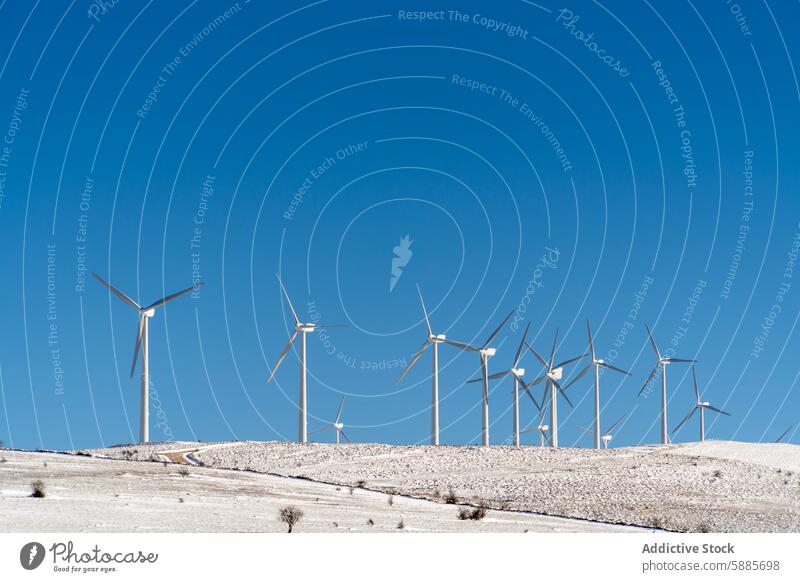 Wind turbines on a snowy hillside promoting green energy wind turbine sustainability renewable environment wind power winter blue sky technology