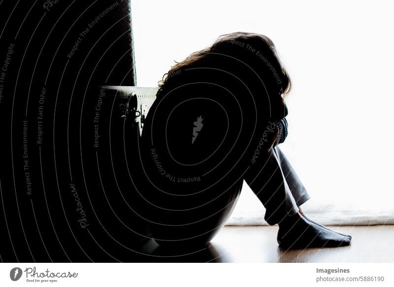 Unhappiness. Woman in silhouette, sitting on the floor with backlight. Depressing thoughts. Silhouette Ground sedentary Back-light depressingly Shadow play
