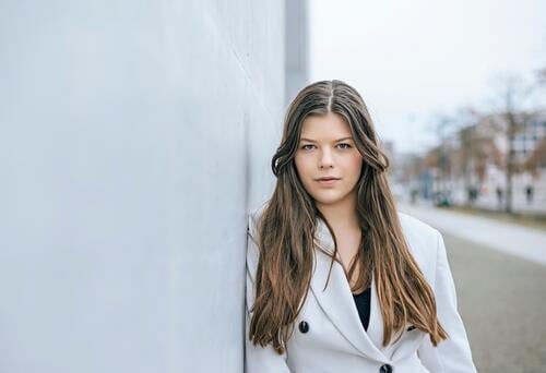 smiling young woman leaning against a wall Woman Smiling relaxed Young woman Meditative sensual Dreamily portrait fortunate youthful Happy Single optimistic