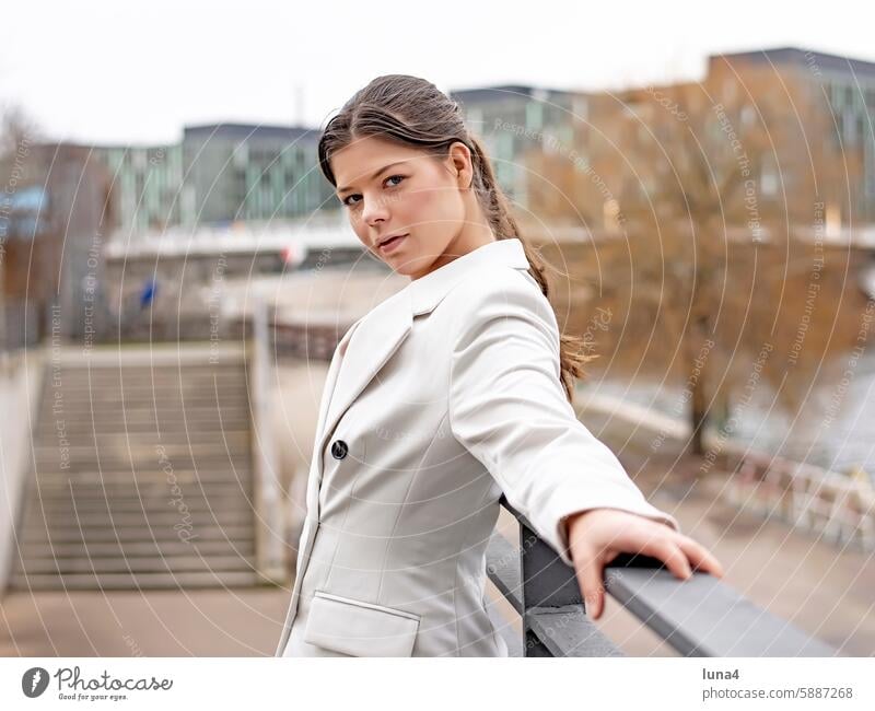 Self-confident young woman stands on a railing in the city Woman relaxed Young woman Meditative sensual Dreamily portrait fortunate youthful Happy Single