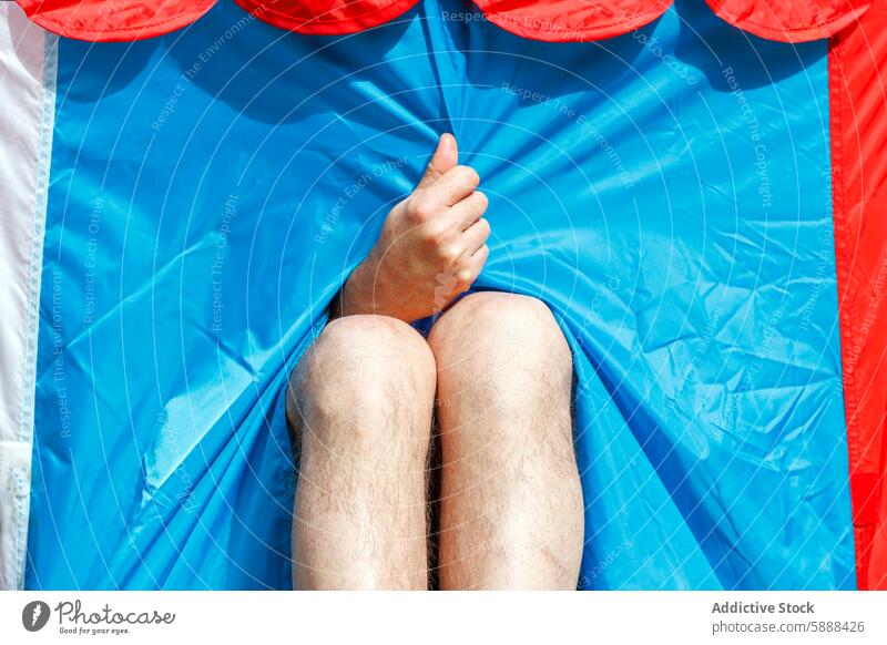 Close-Up of Person Relaxing in Colorful Circus Tent close-up person hand relaxing circus tent colorful red white blue fabric playful whimsical vintage detail