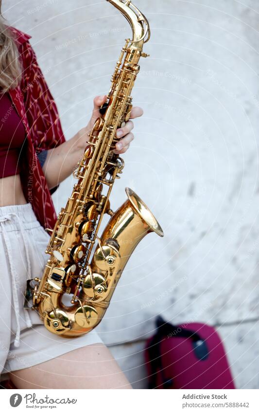 Unrecognizable woman holding saxophone, partial view against white background music instrument jazz golden musical instrument musician style casual outdoor